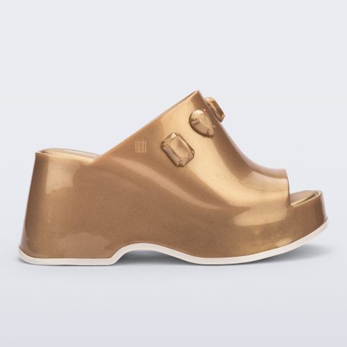 Side view of a metallic gold Patty Stones + Undercover platform open toe mule with beige sole and stone embellishments on upper.