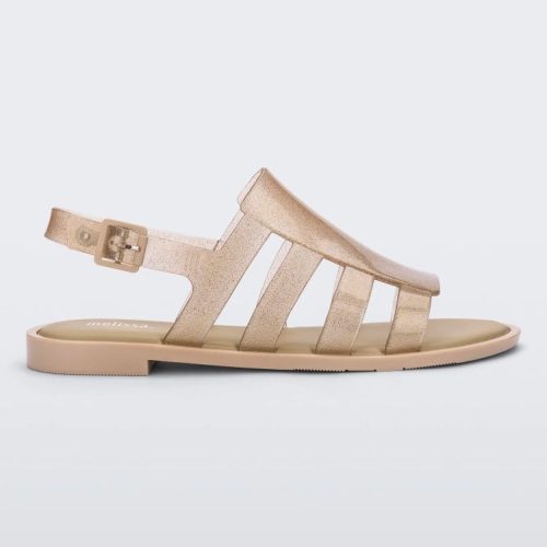 Side view of a transparent glitter beige Melissa Boemia sandal with straps conjoining in the front and a back buckle.