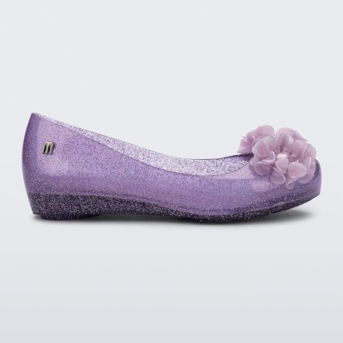 Side view of a clear glitter purple Ultragirl Springtime kids flat with two purple flowers and peep toe.