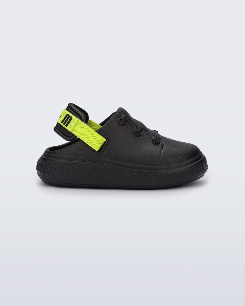 Side view of a black with green back strap Charlie baby sneaker