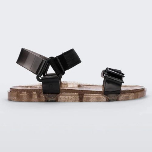 Side view of a Melissa Wide Papete sandal with transparent gold glitter sole with black velcro straps