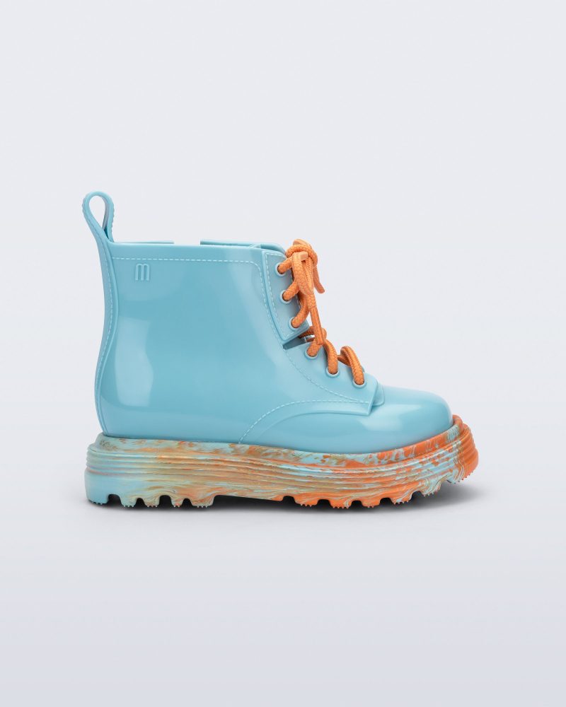 Side view of a blue Coturno baby boot with orange laces.