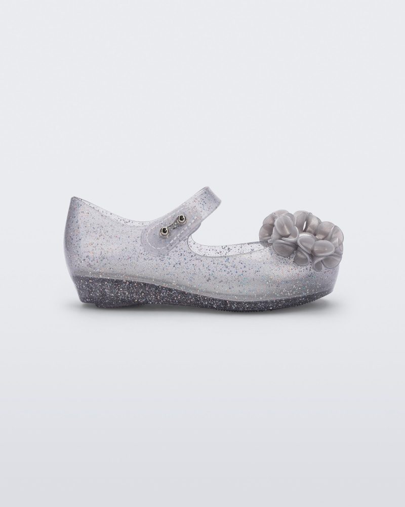 Side view of a clear grey glitter Ultragirl Springtime baby flat with grey flower and peep toe.