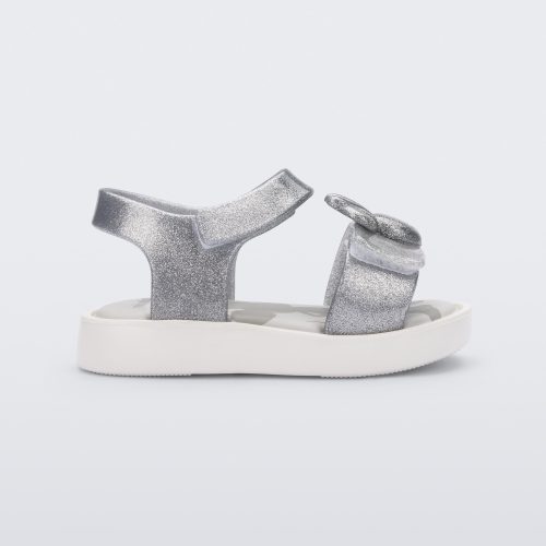 Side view of a white/glitter silver Mini Melissa Jump sandal with a Mickey Mouse logo detail on the front strap and an ankle strap