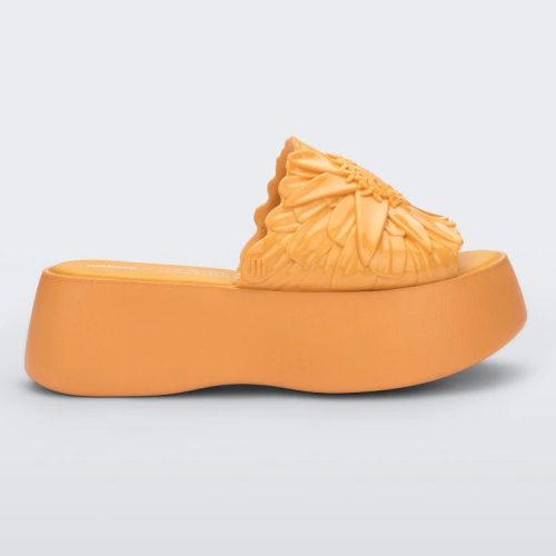 Side view of a yellow Melissa Panc Becky platform slide with a flower on top.