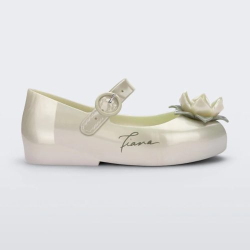 Side view of a Metallic White/Green Mini Melissa Sweet Love Princess flat with a metallic white base with Tiana in script on the side, a top strap, a flower detail on the toe and a drawing of Tiana of The Princess and The Frog on the insole.