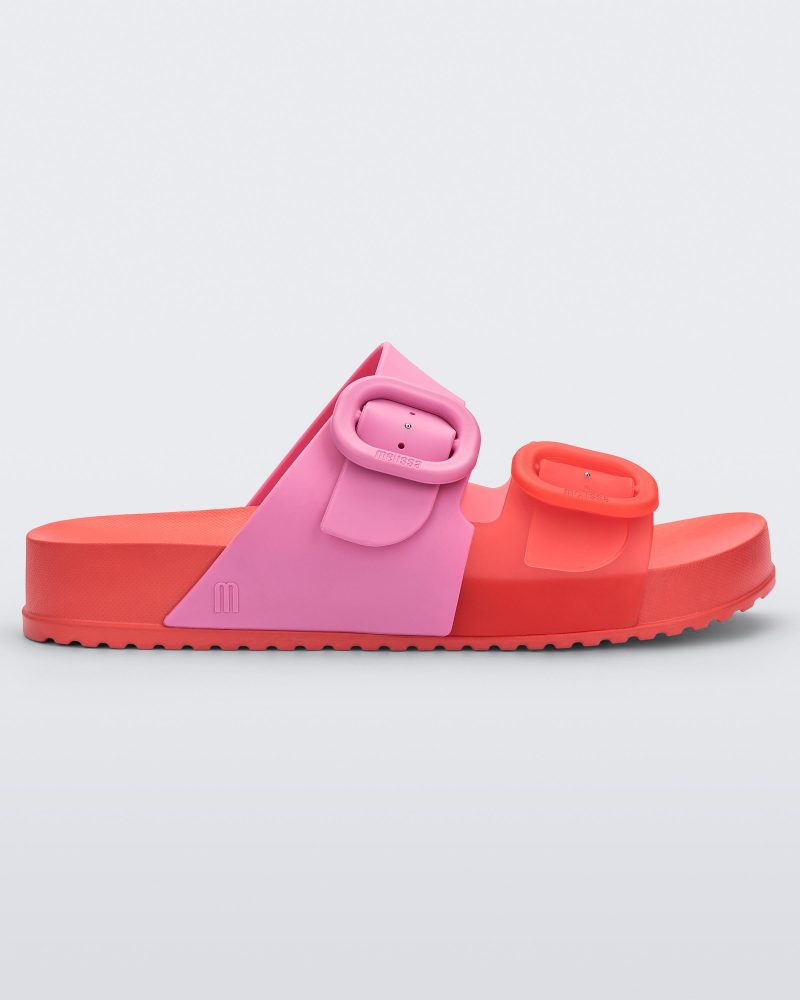 Side view of a Red/Pink Melissa Cozy slide with two red and pink straps with a buckle detail.