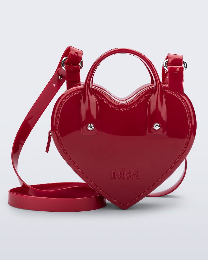 Front view of a red Heartbeat bag with small handles and longer strap.