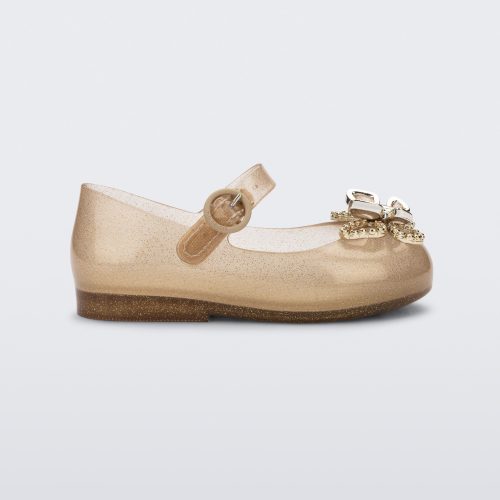 Side view of a glitter beige Mini Melissa Sweet Love Butterfly flat with a top strap and a gold butterfly detail on the toe