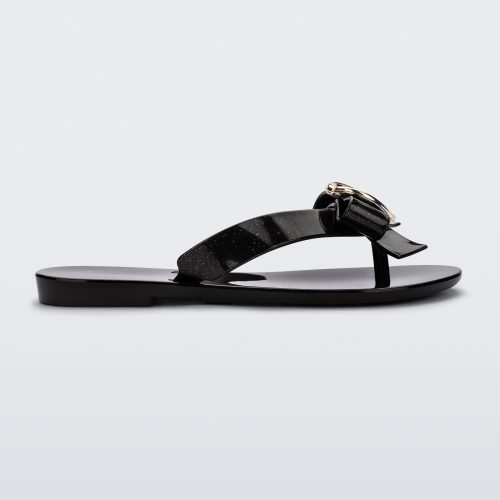 Side view of a black Mini Melissa Harmonic Heart flip flop with a black bow and gold heart detail on the straps