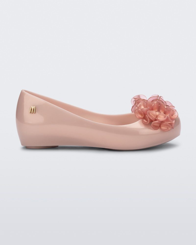 Side view of a pearly pink Ultragirl Springtime kids flat with two clear pink flowers and peep toe.