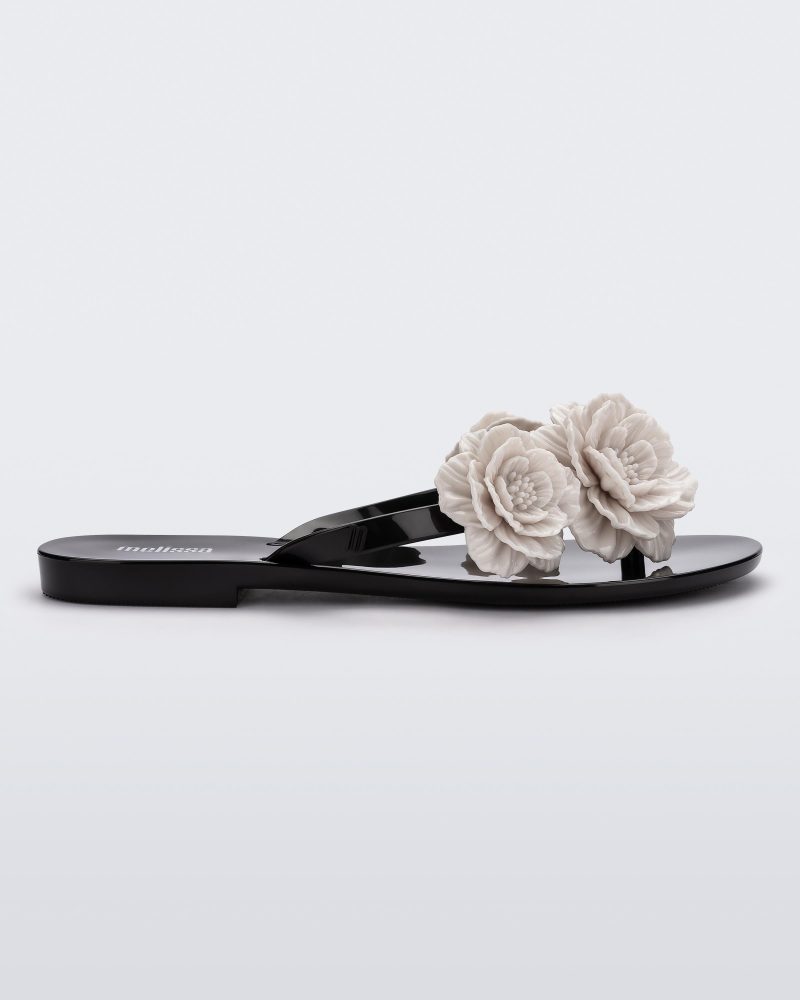 Side view of a black Harmonic Springtime women's flip flop with 3 beige flowers