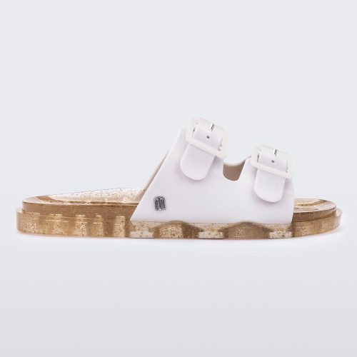 An outter side view of a Beige Mini Melissa Wide Slide with a white top with two white buckles and a beige sole.