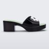 Side view of a Melissa Shape slide sandal in black with platform heel, black front strap with white flower detail and a green insole.