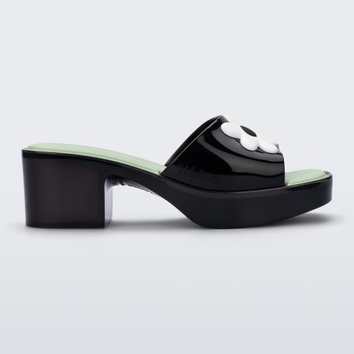 Side view of a Melissa Shape slide sandal in black with platform heel, black front strap with white flower detail and a green insole. 