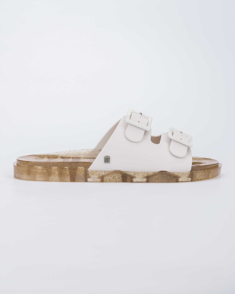 Side view of a Melissa Wide slide sandal with gold glitter sole and white double straps with buckles