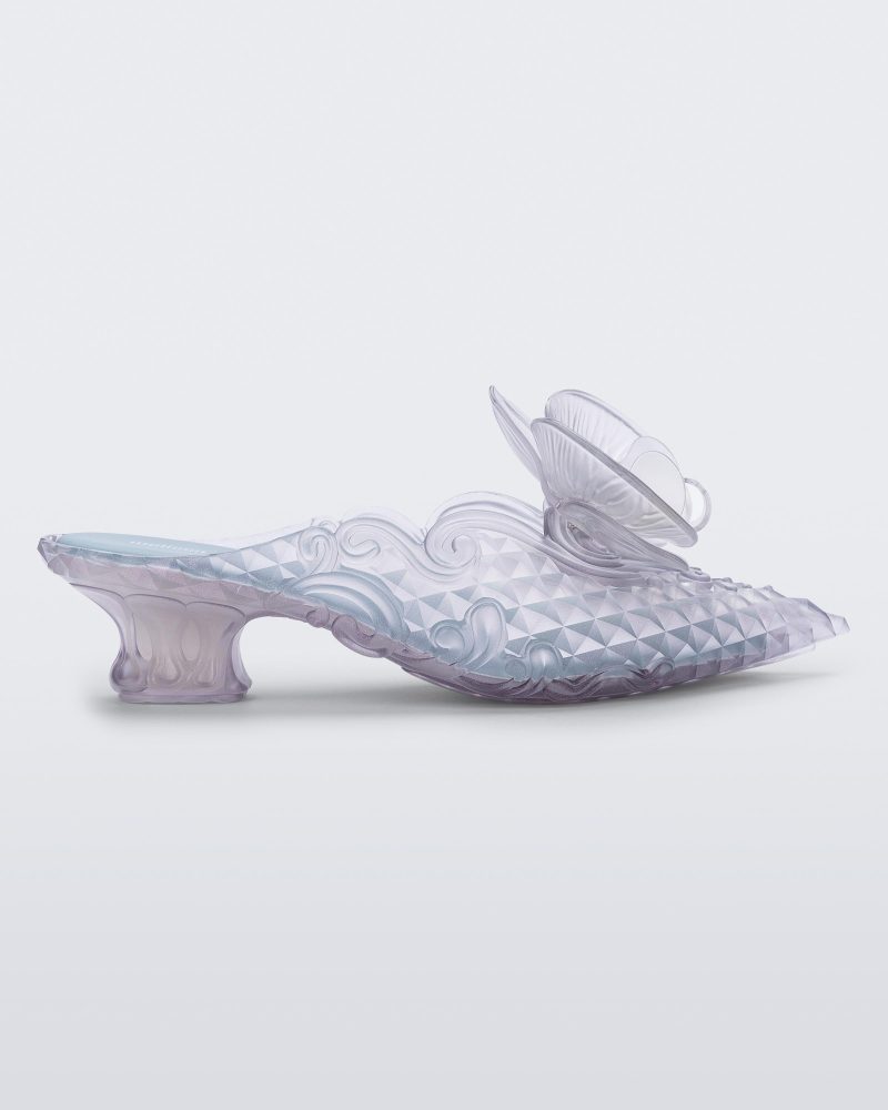 SIde view of a Melissa Flower Court mule in clear with kitten heel and a 3D flower above the toe