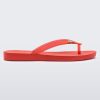 An outter side view of a red Melissa Sun Venice flip flop with a "melissa" logo on the strap.