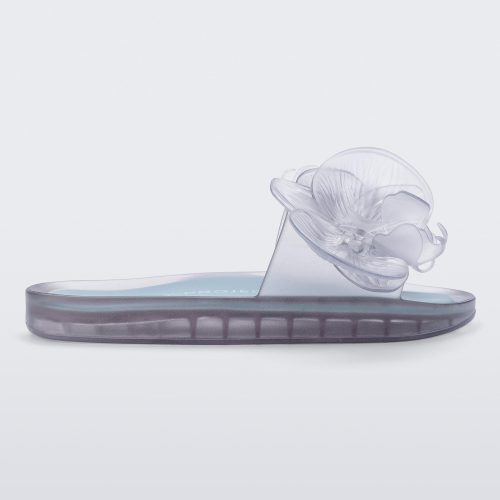 Side view of a Melissa Flower Beach slide in Clear with 3D flower on the strap.