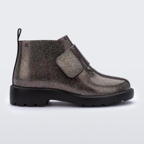 An outter side view of a black/glitter multicolor Mini Melissa Chelsea boot with a glitter multicolor base, velcro front strap and black sole.